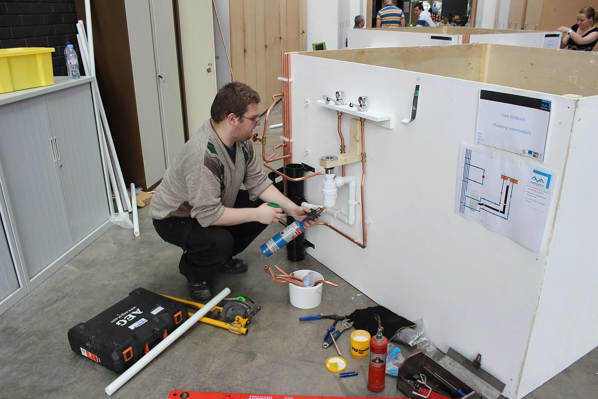 A plumber fitting pipework in a plumbing skills workshop